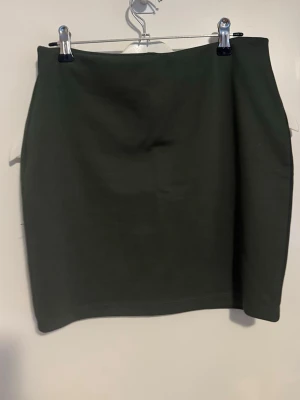 Mörkgrön kortkjol från Cubus - Enkel och stilren mörkgrön kortkjol från Cubus. Kjolen har en rak passform och bred resår i midjan för extra komfort. Använd 1 gång 