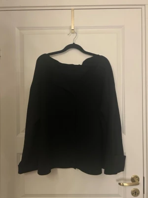 Svart långärmad kofta med knappar - En svart långärmad kofta med knappar framtill. Koftan har en klassisk krage och breda ärmslut, vilket ger en chill och stilren vibe. Perfekt att slänga över en t-shirt eller linne när det blir lite kyligare. Saknar den översta knappen men går att hitta liknande knappar! 