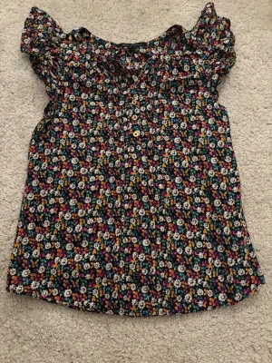 Blommig blus från French Connection - Supersöt blommig blus från French Connection i storlek 8. Toppen har korta puffärmar, rund halsringning och små knappar. Den har färgglada blommor på sig och perfekt i sommar.