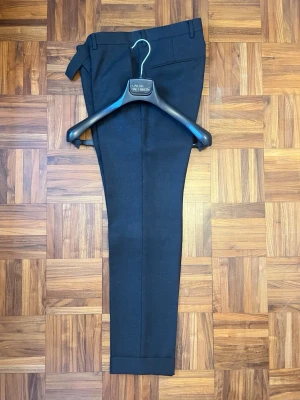 Mörkgrå kostymbyxor Oscar Jacobson - Snygga mörkgrå kostymbyxor från Oscar Jacobson i klassisk rak modell. Byxorna har pressveck, hällor för bälte och är tillverkade i ett mjukt material som känns lyxigt. Perfekta för en stilren look och passar till skjorta eller kavaj. Modell: don trouser. Kan även köpas ihop med kostym jackan.