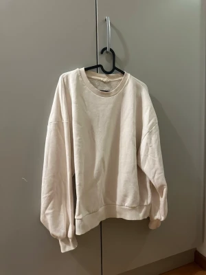 Cremevit collagetröja - Enkel och stilren cremevit collagetröja. Tröjan har rund halsringning, långa ärmar och breda muddar vid ärmslut och nederkant. Perfekt för en chill och avslappnad look. Från GinaTricot i strl. M.