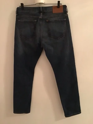 Slim midwaist jeans från H&M - Mörkblå jeans från H&M med slim passform och midwaist. Klassisk femficksdesign, snygga kontrastsömmar och tillverkade i slitstarkt bomullsmaterial. Perfekt för dig som gillar en smal siluett och enkel stil. Strl. 32/32. 