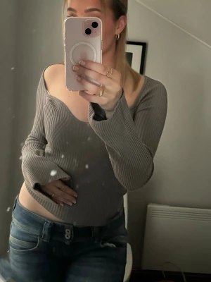 Ribbad grå offshoulder topp - Säljer en snygg ribbad grå topp med offshoulder-design och långa ärmar. Använd ett fåtal gånger men kommer inte till användning längre 💕 Inga defekter, fläckar osv