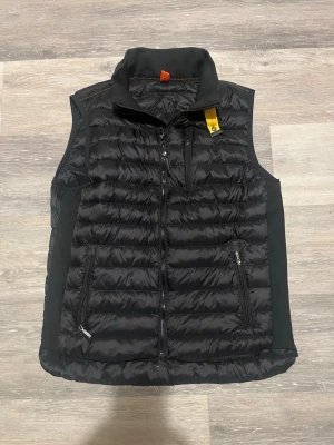 Svart dunväst från Parajumper - Hej, Säljer nu min parajumper väst i strl XL då den blivit lite för kort på mig. I fint skick utan några skador. 