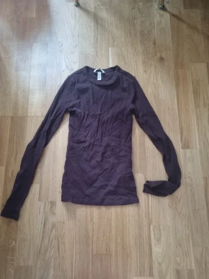 Mörklila ribbad långärmad topp - En enkel och stilren mörklila långärmad topp i ribbad bomull. Modellen är tight och har rund halsringning. 