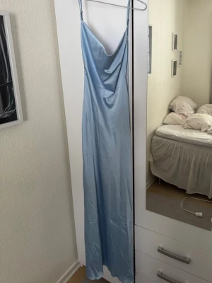 Bal klänning - Jag säljer denna ljusblå satin klänning som jag skulle ha till min bal 2025 men jag ändrade mig och ville ha en gul balklänning så denna kom aldrig till användning. Den är väldigt fin och den passar allt från xs-m då den är lös i passformen, men den är 36. (jag hade spänt den på sista bilden)🩵