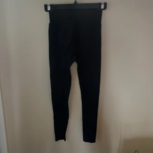 Svarta leggings från New Apparel XS - Svarta leggings från New Apparel i storlek XS. De har hög midja och är tillverkade i ett stretchigt material som sitter tight mot kroppen. Perfekta för en clean och enkel look.