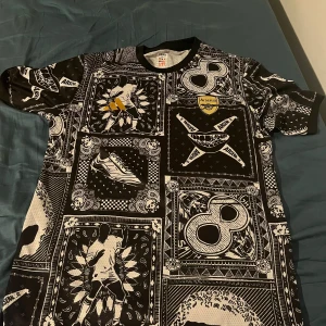 Arsenal svartvit fotbollströja - Unik svartvit Arsenal fotbollströja från Adidas med coolt grafiskt mönster och detaljer som klubbmärke på bröstet. Tröjan har korta ärmar och är tillverkad i ett lätt och ventilerande material, perfekt för dig som vill sticka ut på läktaren eller planen.