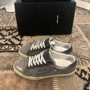 Saint Laurent SL/06  - Box och dustbag är inkluderat, samt de orginella helt oanvända skosnörerna. Skörna är egentligen 40,5 i strl, men de sitter lite stort på mig och jag bär alltid 41. Så rekommenderar att ha 41-42. På skorna sitter ett par lite mörkare skosnören från ett annat par skor. De og skosnören kommer med Skorna är i mycket bra skick, har haft dem sen januari och tagit väl hand om dem. Köpte de från Trendsellers som är trovärdig reseller. Kan sänka pris vid snabb affär. Hör av dig vid minsta lilla fråga!