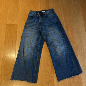 Blå baggy jeans - Säljer ett par blå baggy jeans med breda ben och och fransig kant längst ner. Har använts ett par gånger men är i bra skick 