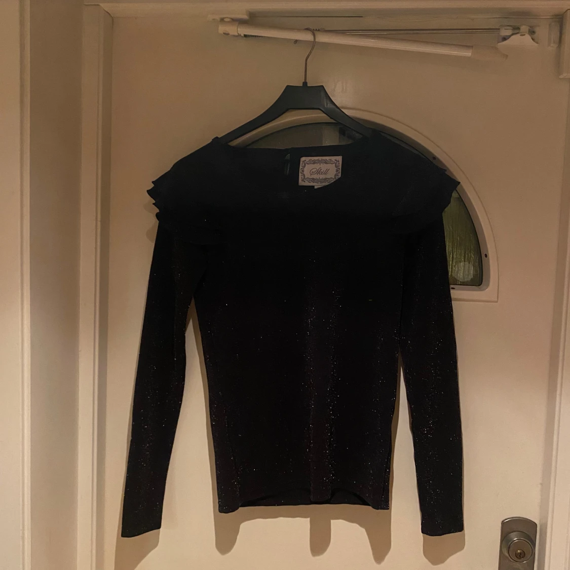 Svart glittrig topp med volang från Skill