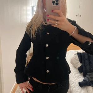 Svart jacka/tröja med silverknappar - Snygg svart kavaj i mocka med figurnära passform och långa ärmar. Jackan har stilrena silverfärgade knappar framtill och en croppad siluett som ger en modern vibe. 