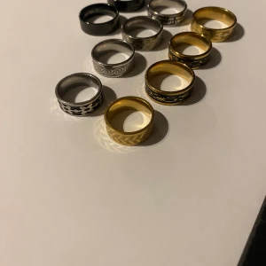 Breda ringar i guld och silver med mönster - Säljer 10st breda ringar i guld- och silverfärg med coola ingraverade mönster som blommor, vågor och geometriska former. Ringarna har en snygg kontrast mellan svart, guld och silver och passar perfekt för dig som vill sticka ut med accessoarer.
