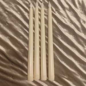 Led ljus  - Bilden visar fyra elektriska LED-ljus i form av stearinljus. De är vita med en låga i plast och passar perfekt för dekoration eller stämningsbelysning. Ljusen ser ut att vara i gott skick utan synligt slitage. Batteridrivna och säkra alternativ till vanliga ljus.