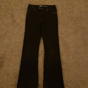 Svarta bootcut jeans LAB Industries - Svarta jeans från LAB Industries i klassisk bootcut-modell. Snyggt utsvängda ben och normal passform. Jeansen har fem fickor och stilrena detaljer, perfekta för dig som gillar en tidlös look.
