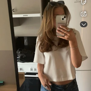 Vit croppad topp med vida ärmar - Säljer en stilren vit croppad topp med korta, vida ärmar och rund halsringning. Toppen har en enkel och clean design som passar perfekt till jeans eller kjol. Materialet känns mjukt och lätt, vilket gör den skön att bära under varmare dagar.