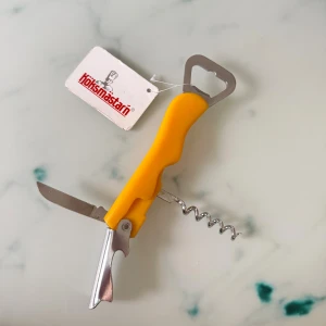 Köksmästarn Multiverktyg Öppnare - Praktiskt multiverktyg från Köksmästarn med flasköppnare, korkskruv och kniv. Ergonomiskt gult handtag och robust konstruktion. Perfekt för köket eller picknicken. Produkten är oanvänd med originaletikett och i nyskick.