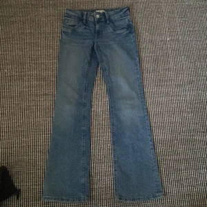 Blå bootcut jeans från Gina Tricot - Snygga blå jeans från Gina Tricot i storlek 164. Modellen har klassisk femficksdesign, bälteshällor och bootcut-ben. Jeansen är tillverkade i mjukt denimtyg och har en låg midja. Perfekta för dig som gillar en tidlös och trendig look.