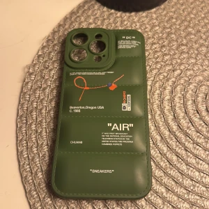 iPhone 16 PRO Max grönt Style Skal - Stilrent grönt skal till iPhone 16 PRO Max med Off-White-inspirerad design. Skalet är i gott skick utan synliga repor eller skador. Ger din mobil ett unikt och trendigt utseende samtidigt som det skyddar mot stötar och repor. Fluffigt skal 