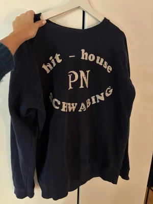 Marinblå Rolling Stones sweatshirt  - Cool marinblå sweatshirt från Rolling Stones x Dressmann med tryck 'hit-house PN Schwabing' i vitt framtill. Har använt den oversized (har vanligtvis strl xs-m)