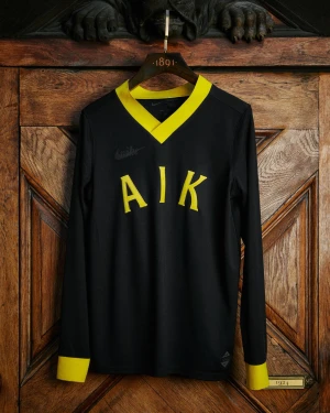 Officiel limited edition Svart AIK långärmad fotbollströja Nike - Limited edition Snygg svart långärmad AIK fotbollströja från Nike med gula detaljer på krage och ärmslut. Klassisk V-ringning och tydlig AIK-text framtill. Perfekt för dig som vill sticka ut på läktaren eller i stan. 