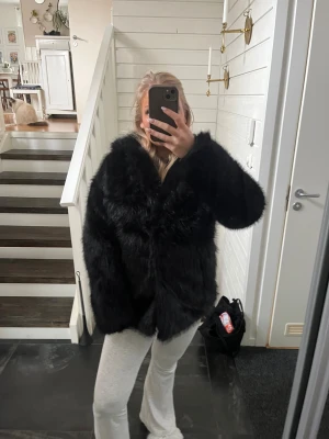 Svart pälsjacka med oversized passform - Säljer en svart pälsjacka med fluffig känsla och oversized passform. Jackan har lång ärm och är helsvart utan synliga detaljer eller mönster. Perfekt för dig som vill ha en statementjacka med mycket volym och cool look.