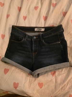 Mörkblå jeansshorts från ONLY - Snygga mörkblå jeansshorts från ONLY med uppvikta ben. Perfekta för en chill sommardag och passar till allt. Ganska lågmidjade.