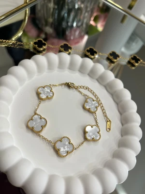 18k guldpläterad klöver armband i vitt - Ett elegant armband i högkvalitativt rostfritt stål, pläterat med 18k guld. Det vackra klöverhänget (15 mm) ger ett tidlöst och lyxigt uttryck. Perfekt som både vardagssmycke och gåva.🌸