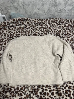 Beige stickad tröja off shoulder Gina Tricot - Supermjuk beige stickad tröja från Gina Tricot i storlek S och inte använd. Tröjan har ett snyggt kabelstickat mönster, bred ribbad kant och offshoulder-passform. Perfekt för lager på lager och chill höst- och vinterstil.