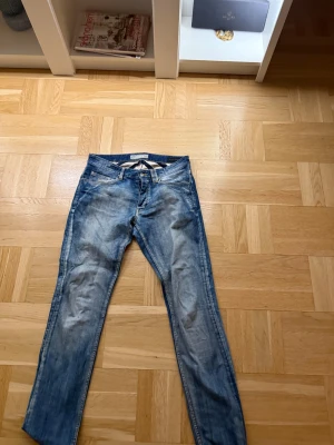 Replay Anbass ljusblå jeans - Säljer ett par AT.P.Co jeans i ljusblå tvätt med snygga slitningar och klassisk femficksdesign. Jeansen har smal passform och raka ben, med dragkedja och knapp i midjan. Perfekt för dig som gillar en modern och avslappnad stil. Som ny använd 1 gång 