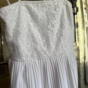 Studentklänning / vit klänning  - Vit klänning från veromoda storlek 34. Spets upptill och veckat tyg nertill, dragkedja i ryggen. Axelband som går att ta av. Endast använd en gång🤍