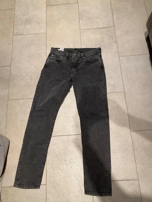 Levi's 502 svarta jeans W32 L34 - Säljer ett par svarta Levi's 502 jeans med klassisk femficksdesign och raka ben. Jeansen har en snygg mörk tvätt och är tillverkade i slitstarkt bomullsjeans. Perfekta för dig som gillar en tidlös och clean look.