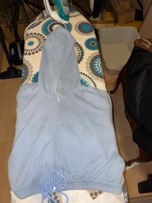 Ljusblå hoodie från H&M med dragkedja - Ljusblå hoodie från H&M i storlek S. Tröjan har huva, hel dragkedja framtill och snörning vid nederkanten. Tillverkad i mjuk bomullsmix med långa ärmar och ribbade muddar. Perfekt för chill dagar eller när du vill vara extra comfy. Finns fläcka som ej går bort där av priset och nåt hål på armen 