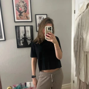 Svart lyxig t-shirt - En enkel svart t-shirt med korta ärmar, den är lite tjockare i materialet vilket gör att den ser och känns lyxig . Toppen har en loose passform och är perfekt för dig som gillar en chill och avslappnad stil. Materialet känns mjukt och lätt mot huden, vilket gör den skön att bära hela dagen.