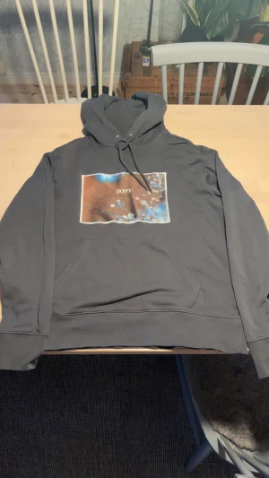 grå hoodie J.Lindeberg med print - Säljer en grå hoodie från J.Lindeberg i bomull med stor magficka och huva med snörning. På bröstet finns ett färgstarkt print med texten 'DON'T' i mitten. Skön passform och perfekt för chill dagar.