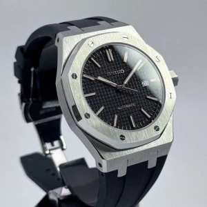 Seikmod royal oak rubber strap - Stilren Seiko automatisk klocka med svart texturerad urtavla, silverfärgade index och visare samt datumvisning. Boetten är åttakantig i borstat silver och armbandet är svart och sportigt. Perfekt för dig som gillar modern design och detaljer.