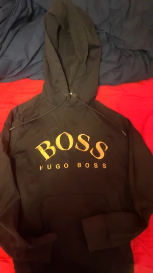Hugo boss hoodie - Svart hoodie från hugo boss med tryck på bröstet i färgen guld perfekt för vardags användning och passar perfekt med jeans.