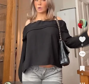 Svart offshoulder blus från Quiz - Säljer en svart blus från Quiz med offshoulder-design och bred volang runt halsen. Blusen har långa ärmar med resår vid ärmslut och är gjord i ett lätt, flowy material som ger en snygg siluett. Perfekt för dig som gillar stilrena och trendiga plagg.