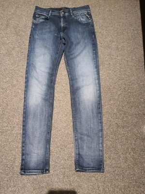 Replay blå jeans Kyele slim fitted - Snygga blå jeans från Replay, modell Kyele. De har en slim passform med klassisk femficksdesign och dragkedja med knapp. Jeansen är tillverkade i jeansmaterial med lätt tvättad look och ljusa partier på framsidan. Perfekta för dig som gillar sköna jeans. waist 28 lenght 29.