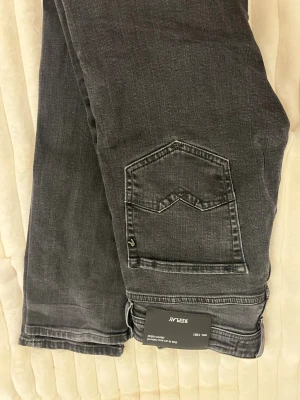 Replay svarta jeans  - Svarta jeans från Replay med comfort fit och klassisk femficksdesign. Jeansen har en snygg tvättad look, raka ben och tydliga sömmar på bakfickan. Perfekt för dig som gillar stilrena och bekväma jeans. W28, L32. Hör av dig vid minsta lilla fundering!