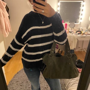 Randig stickad tröja i marinblått och vitt - Säljer en oversized stickad tröja med breda marinblå och vita ränder. Tröjan har lång ärm, rund halsringning och är riktigt mysig och perfekt för kyliga dagar. Passformen är loose och materialet känns mjukt och skönt mot huden.