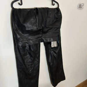 Svarta skinnbyxor från Zara M - Säljer ett par svarta skinnbyxor från Zara i storlek M. Byxorna har raka ben, stora fickor fram och en snygg, lite loose passform. Perfekta för dig som vill ha en edgy look med streetkänsla.