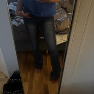 Mörkblå bootcut jeans med låg midja - Säljer ett par mörkblå jeans med snygg bootcut och låg midja. Jeansen har klassisk femficksdesign, smal passform upptill och lätt utsvängda ben. Tillverkade i stretchigt denim för en bekväm känsla. Perfekta till sneakers eller boots.