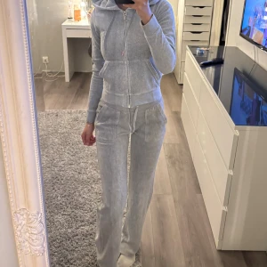 Juicy Couture set - Säljer mitt fina ljusgråa Juicy set. Storlek xxs på båda. Byxorna är lite nött nertill (sista bilden) men syns knappt. Koftan är knappt använd, byxorna lite mer använda. Skulle säga att byxorna passar som xs. Skriv för fler bilder eller frågor💋