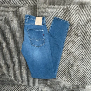 Replay Anbass jeans blå - Säljer ett par Replay Anbass Hyperflex jeans i klassisk blå tvätt. Slim fit-modell med fem fickor, snygga sömmar på bakfickorna och bekväm stretch. Perfekta för dig som gillar en smalare passform och vill ha jeans som sitter snyggt hela dagen.