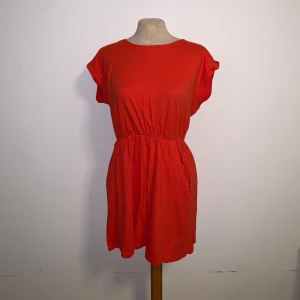 Röd kortärmad klänning  - Enkel och snygg röd kortklänning med jättelång material och fickor från HM. Storlek S