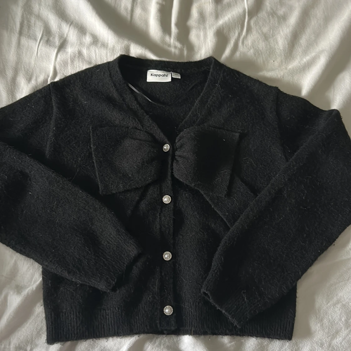 Svart kofta med rosett från Kappahl