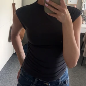 Svart topp - Säljer en superfin mörkgrå, tight topp med rund hals och lite veckad på sidorna. Tröjan är från Ginatricot🤍