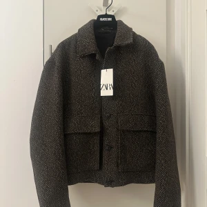 Nytt Rutig jacka från Zara  - Snygg jacka från Zara i mörkbrun och beige rutig. Jackan har klassisk krage, stora fickor framtill och stängs med knappar. Perfekt för lager-på-lager och ger en cool, avslappnad vibe till din outfit.