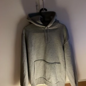 Grå hoodie från Selected Homme - Snygg grå hoodie från Selected Homme med klassisk känguruficka och dragsko i huvan. Perfekt för chill dagar eller när du vill ha en enkel och stilren look. Mjuk insida och långärmad modell.